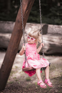 View of girl playing on swing at park