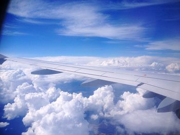 Cropped image of airplane flying over clouds