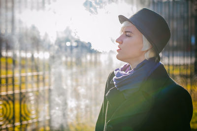 Young woman smoking while standing at park