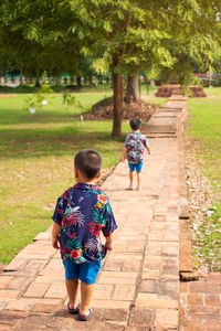 Rear view of boys walking on footpath