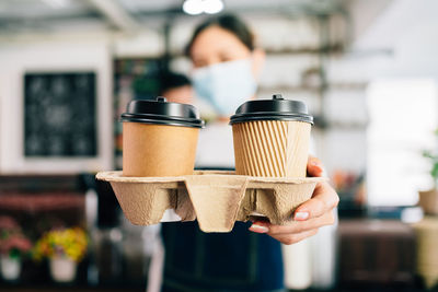 Close-up of woman giving coffee cup while standing at cafe