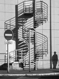Low angle view of spiral staircase against building with person's shadow