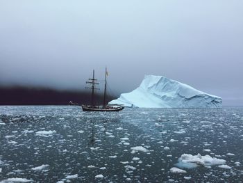 Ship sailing by iceberg in sea during foggy weather