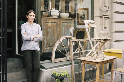 Portrait of owner with arms crossed standing at store