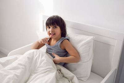 Child boy lies in a white children's bed with a blanket in a room with toys rabbits hug