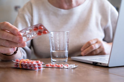 Midsection of woman using laptop on table