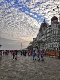 Group of people on building against cloudy sky