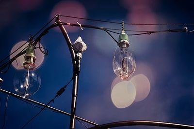 Low angle view of illuminated light bulb against sky