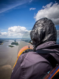 Pilot flying autogyro over elbe river against sky