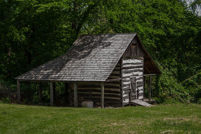 Wooden house amidst trees on field