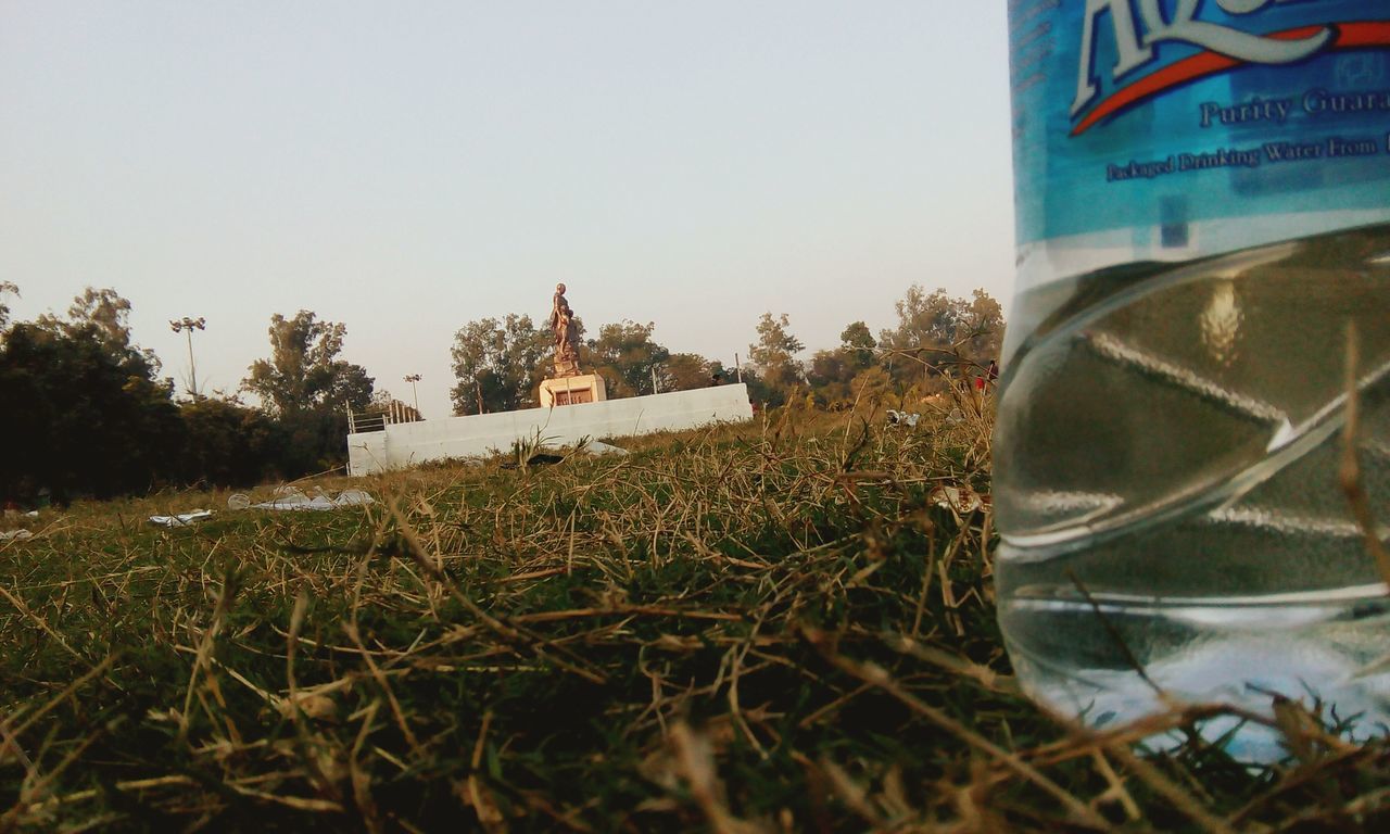 clear sky, field, abandoned, grass, plant, day, text, growth, obsolete, no people, outdoors, damaged, copy space, close-up, built structure, dry, building exterior, western script, architecture, sky