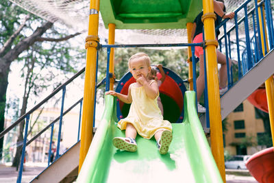 Full length of happy girl on slide at playground