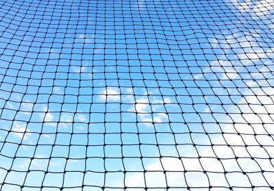 Detail shot of net against blue sky and clouds