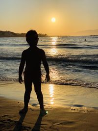 Silhouette man standing on beach against sky during sunset