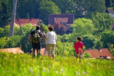 Rear view of people walking on grassland