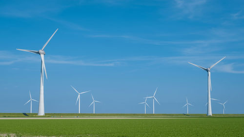 Windmills on field against sky