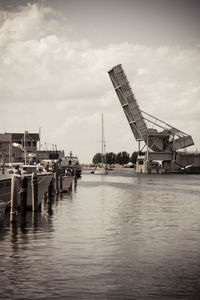 Cranes at harbor against sky in city