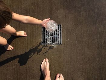 High angle view of girl pouring water on footpath