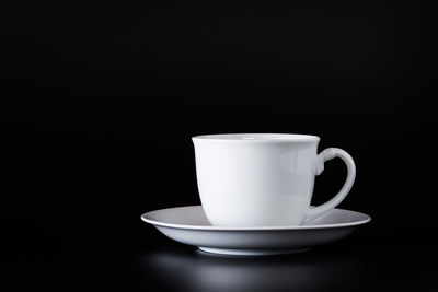 Close-up of coffee cup on table against black background