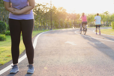 Low section of woman with bicycle on road