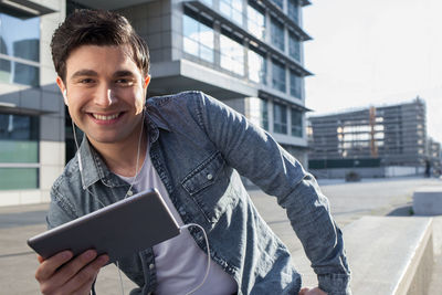 Portrait of young man using digital tablet while standing outdoors
