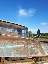 Abandoned car against blue sky