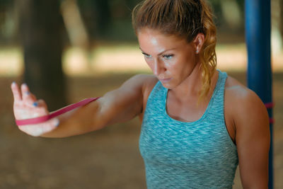 Woman exercising with elastic band outdoors in the fall, in public park