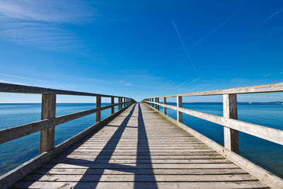 Pier over seascape against blue sky