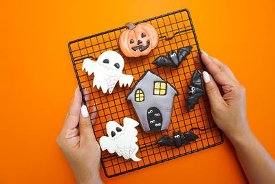 Women's hands hold gingerbread cookies on the baking rack for halloween celebration