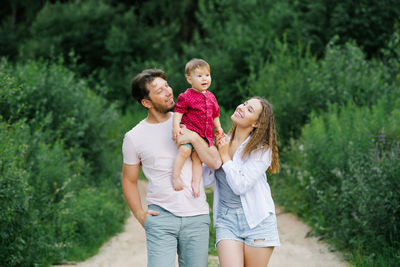 A happy and joyful family with a young son walks through the forest in the summer. healthy lifestyle