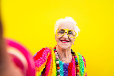 Portrait of smiling woman wearing colorful clothing against yellow background