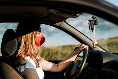 Side view of woman wearing flu mask sitting in car