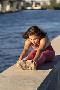 Full length of woman sitting on pier