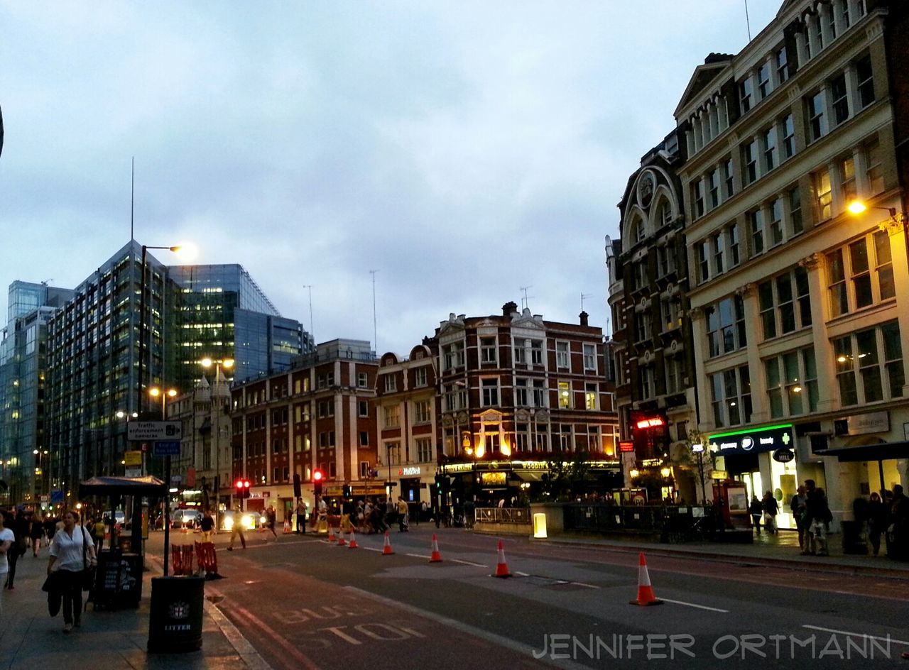 building exterior, architecture, city, built structure, street, sky, city life, city street, large group of people, road, street light, cloud - sky, building, illuminated, transportation, outdoors, car, person, zebra crossing