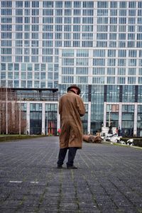 Rear view of man walking on sidewalk against buildings