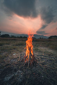 Bonfire on field against sky during sunset