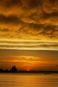 Scenic view of sea against dramatic sky during sunset