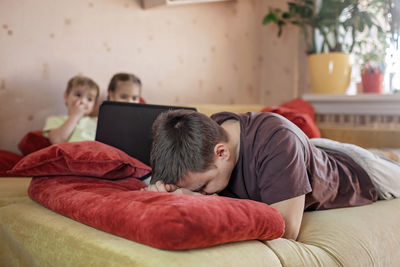 Rear view of people relaxing on bed at home