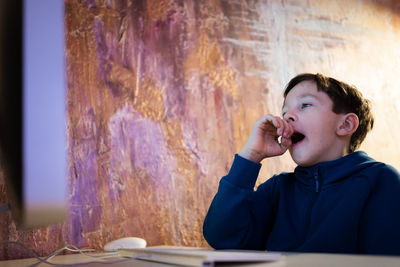 Boy yawns at the computer, boredom and tired