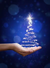 Close-up of hand holding illuminated christmas tree at night