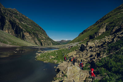 Rear view of man standing on rock by lake