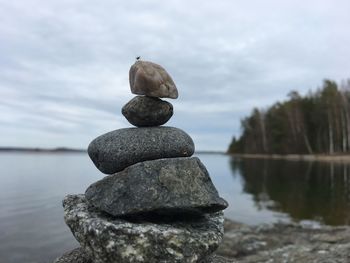 Stack of pebbles in water against sky