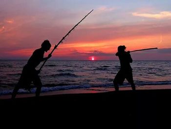 Silhouette of people on beach at sunset