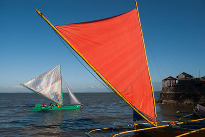 Boat sailing on sea against clear blue sky