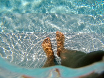 Low section of woman standing on steps in swimming pool