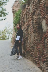 Portrait of woman standing against brick wall