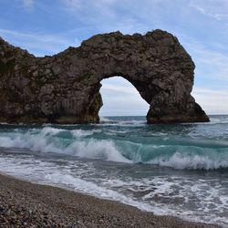 Waves reaching shore at beach by rock formations