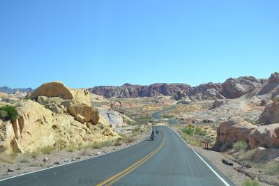 Road amidst mountains against clear sky