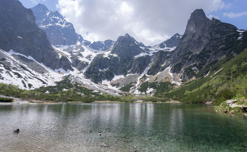 Beautiful greenish alpine tarn surrounded by rocky mountains with remaining snow, slovakia, europe