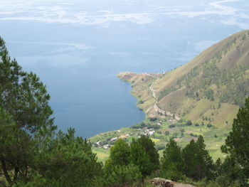 High angle view of trees and sea against mountains